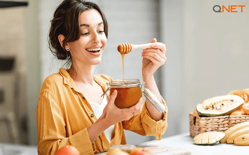 A young woman relishing QNET’s Nutriplus Monofloral Honey in her kitchen