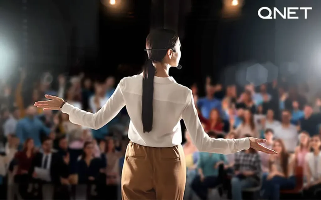 A women addressing a gathering on stage