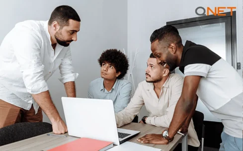 people at a meeting on a table looking at computer
