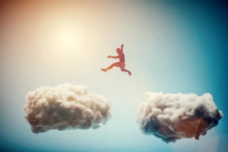 person jumping across two clouds