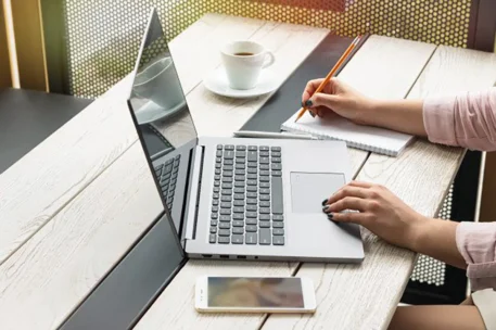 young woman writing on laptop